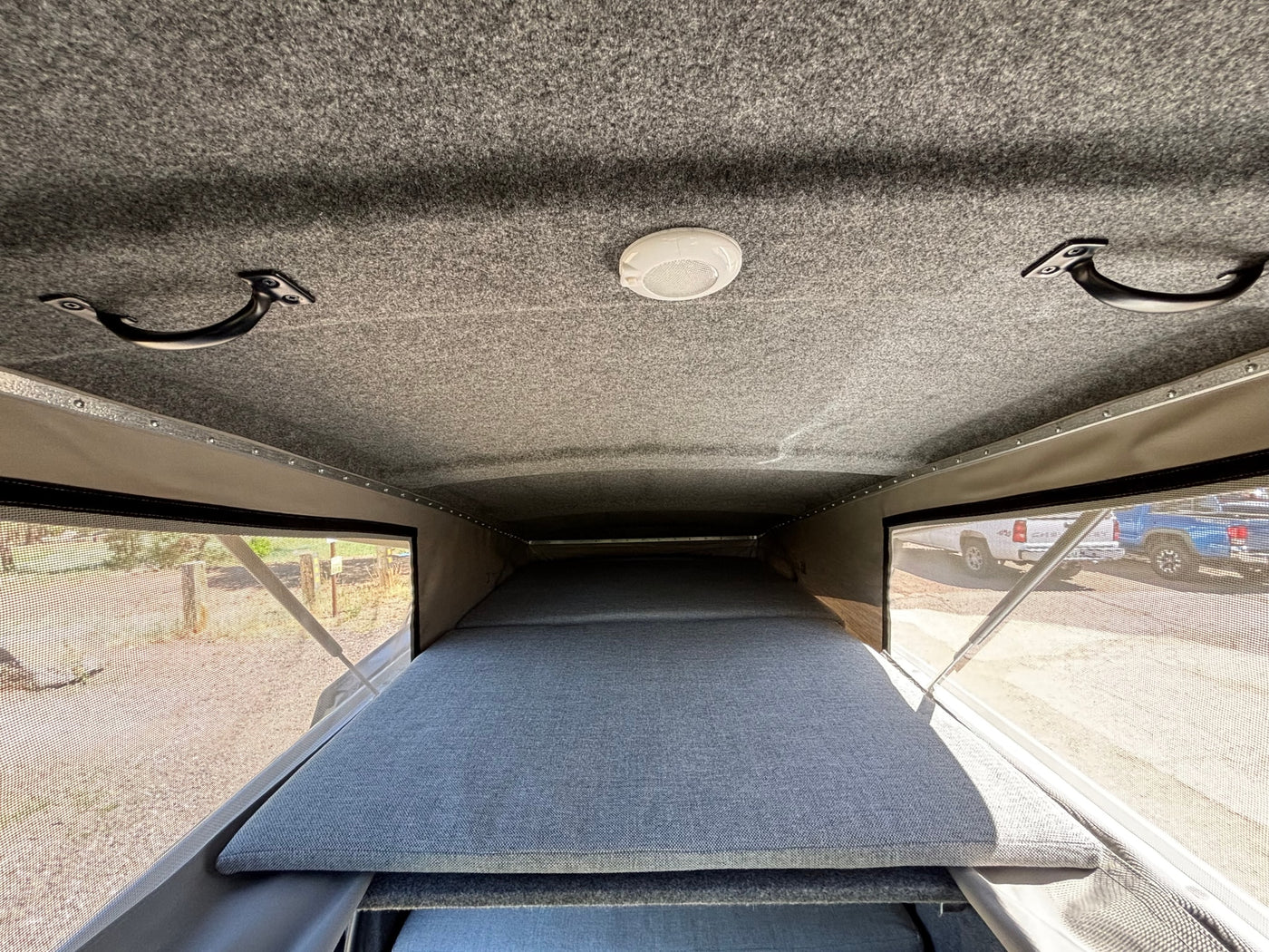 RV rental interior view: pop-top camper with a large grey bed, ceiling light, and grab handles. — photo 3