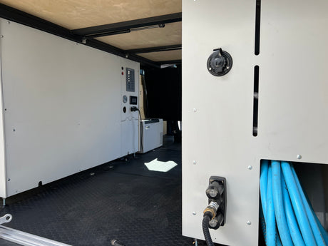 RV rental interior: organized utility panel with power, water connections, and hose storage in a customized camper van.
