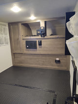 rv rental: RV interior with wood-look cabinets, multimedia control panel, TV mount, and textured utility flooring.
