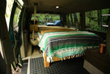Cozy camper van interior: bed, pillows, bike, forest view. Perfect for RV rental adventures.