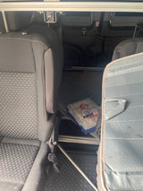 RV rental interior: passenger seats, first aid kit on the diamond plate floor, and overhead storage rails.