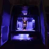 Cozy blue-lit RV rental interior from open rear doors, showing bunk beds & a front sleeping platform.