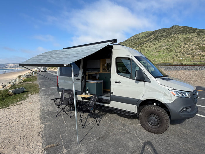  and supplies by a sink and window.|Organized RV rental kitchen interior featuring under-sink storage