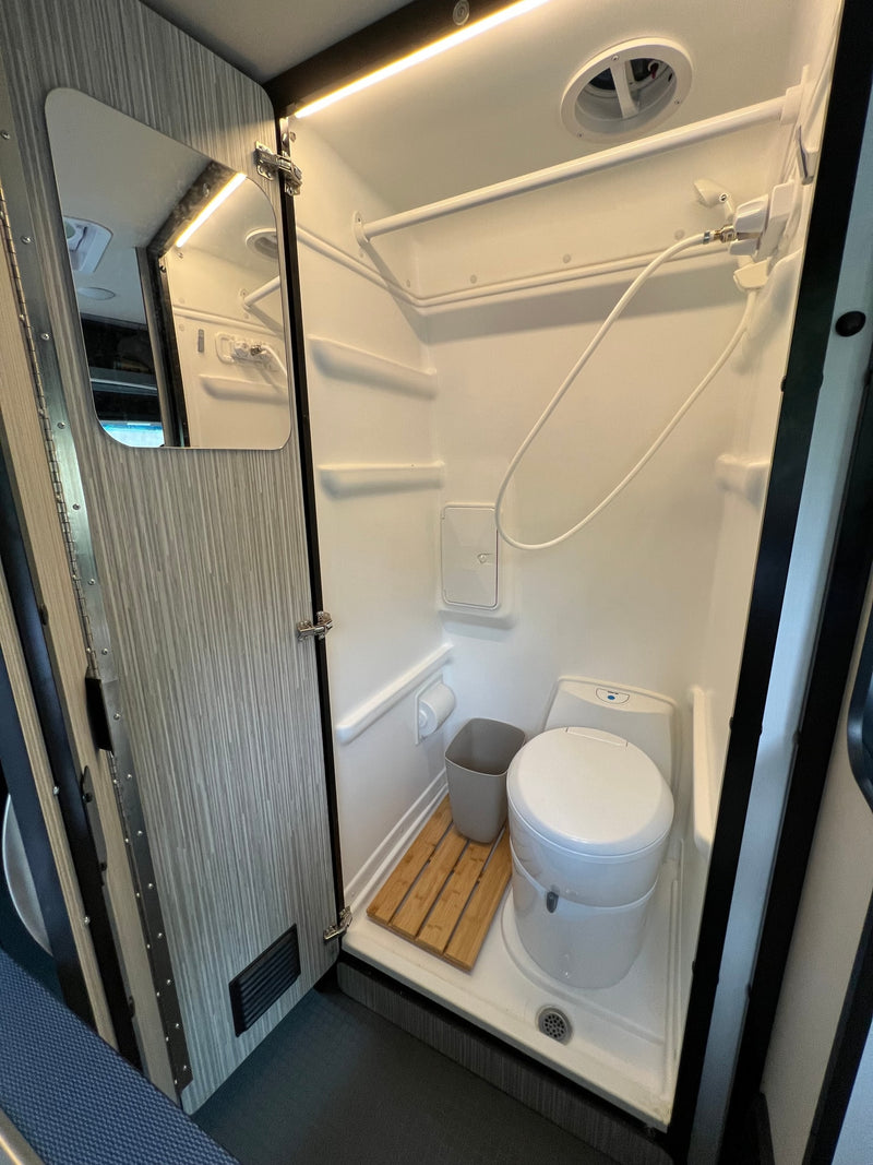 Inside an RV rental: a compact wet bath with shower, toilet, wooden mat, and LED lighting, designed for small spaces. — photo 12