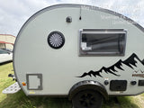 Light gray **rv rental** travel trailer with black mountain graphics and unique round window, ready for your next outdoor adventure.