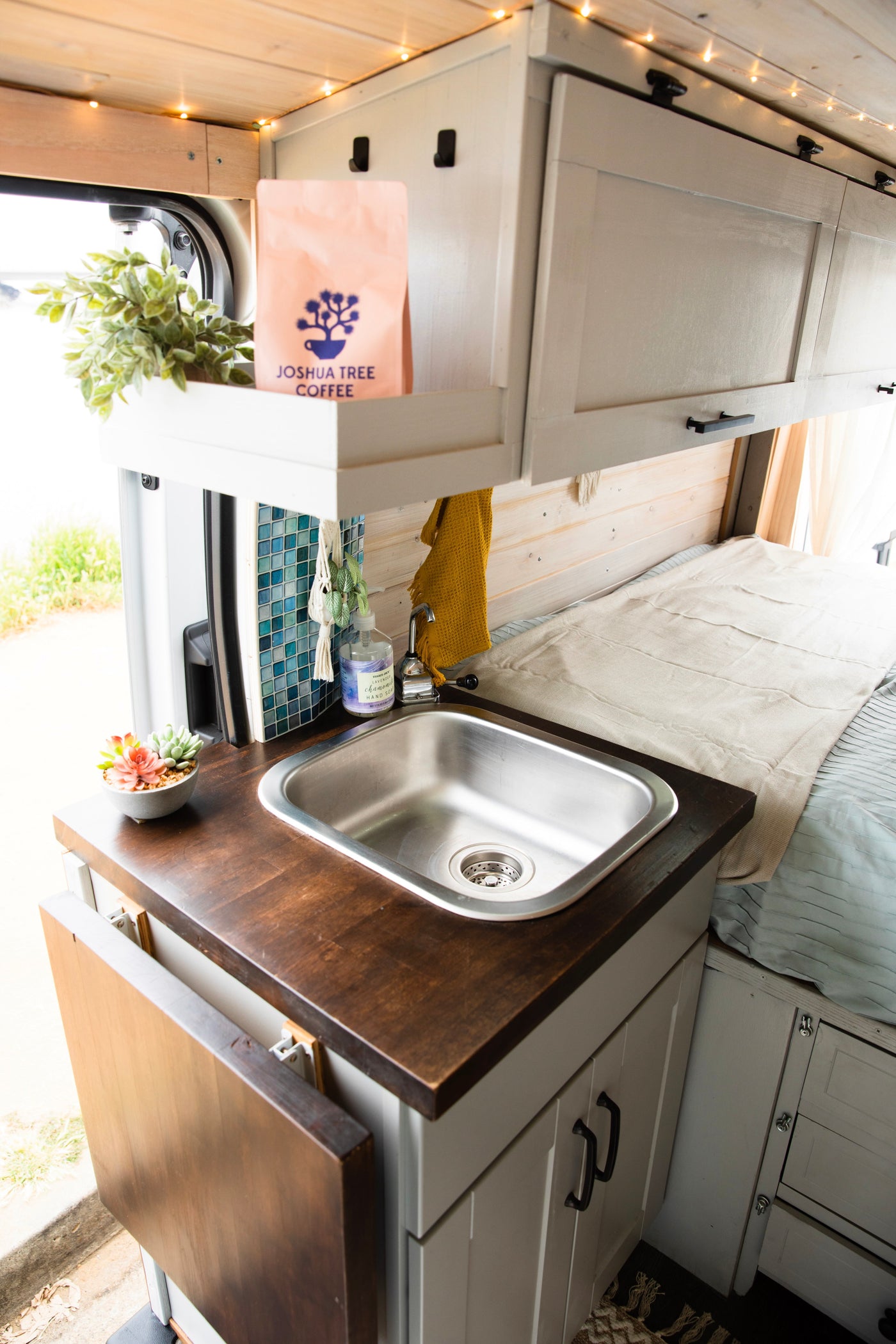 Warm-lit RV rental interior featuring a compact kitchen, sink, and sleeping area with wooden accents. — photo 5
