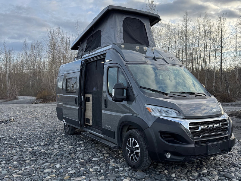  is parked on a rocky riverbank for outdoor adventure.|This gray pop-top camper van — photo 3