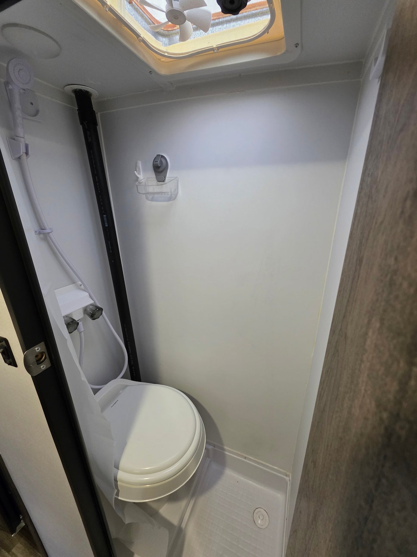 This RV rental bathroom features a compact wet bath with a toilet, handheld shower, and ceiling vent fan. — photo 5