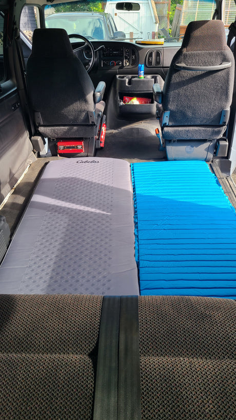 Van interior converted for travel, featuring dual sleeping pads. Ideal RV rental choice!