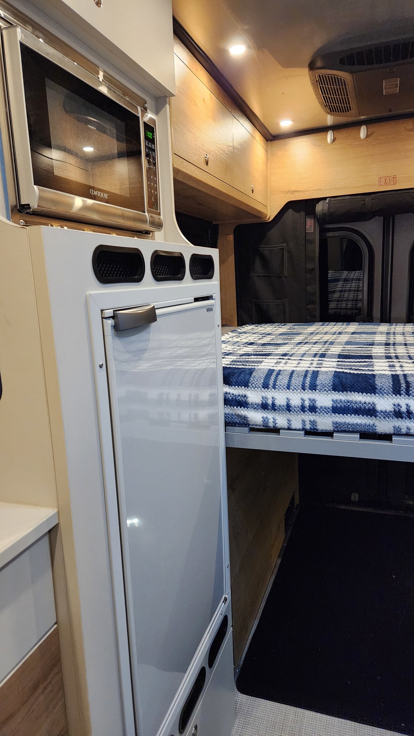 RV rental interior: cozy bed, microwave, and fridge. Designed for comfort and convenience in a compact living space.