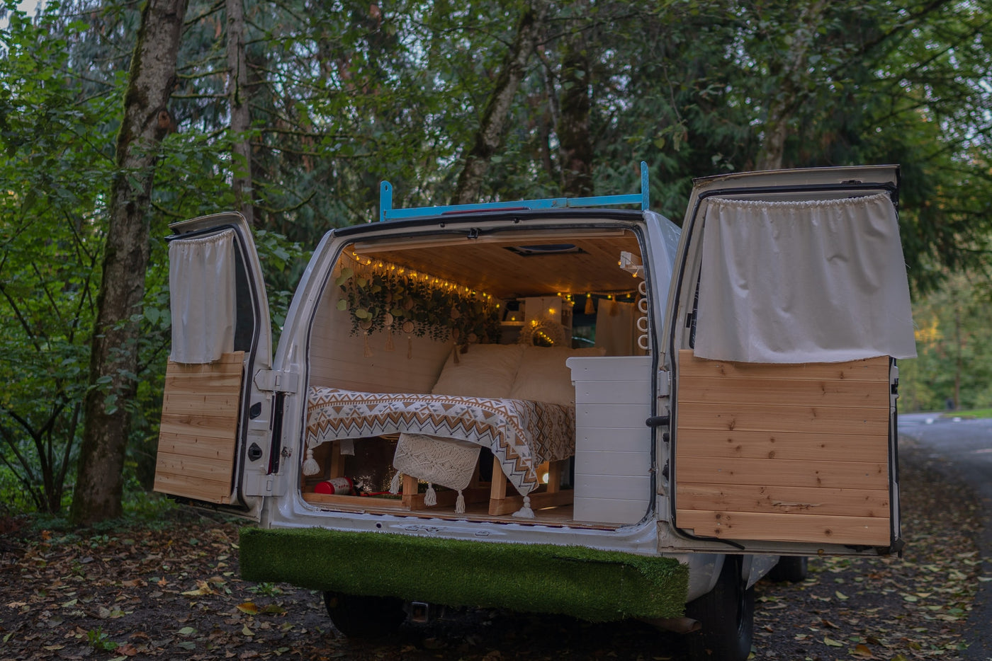 Cozy custom camper van with open back doors, showing a bed, lights, and wood interior, ideal for an RV rental adventure. — photo 12
