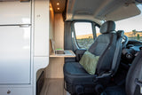 Modern RV rental interior: workspace with laptop, comfy seat, and stunning desert views through the window.