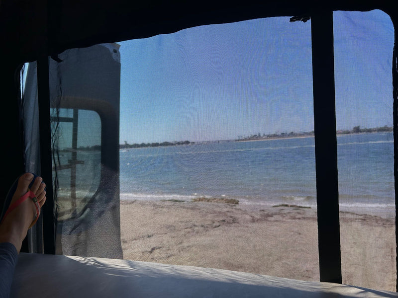  foldable table & scenic water/park view.|A gray Mercedes Sprinter RV rental parked at a wooded campsite with two happy dogs — photo 12