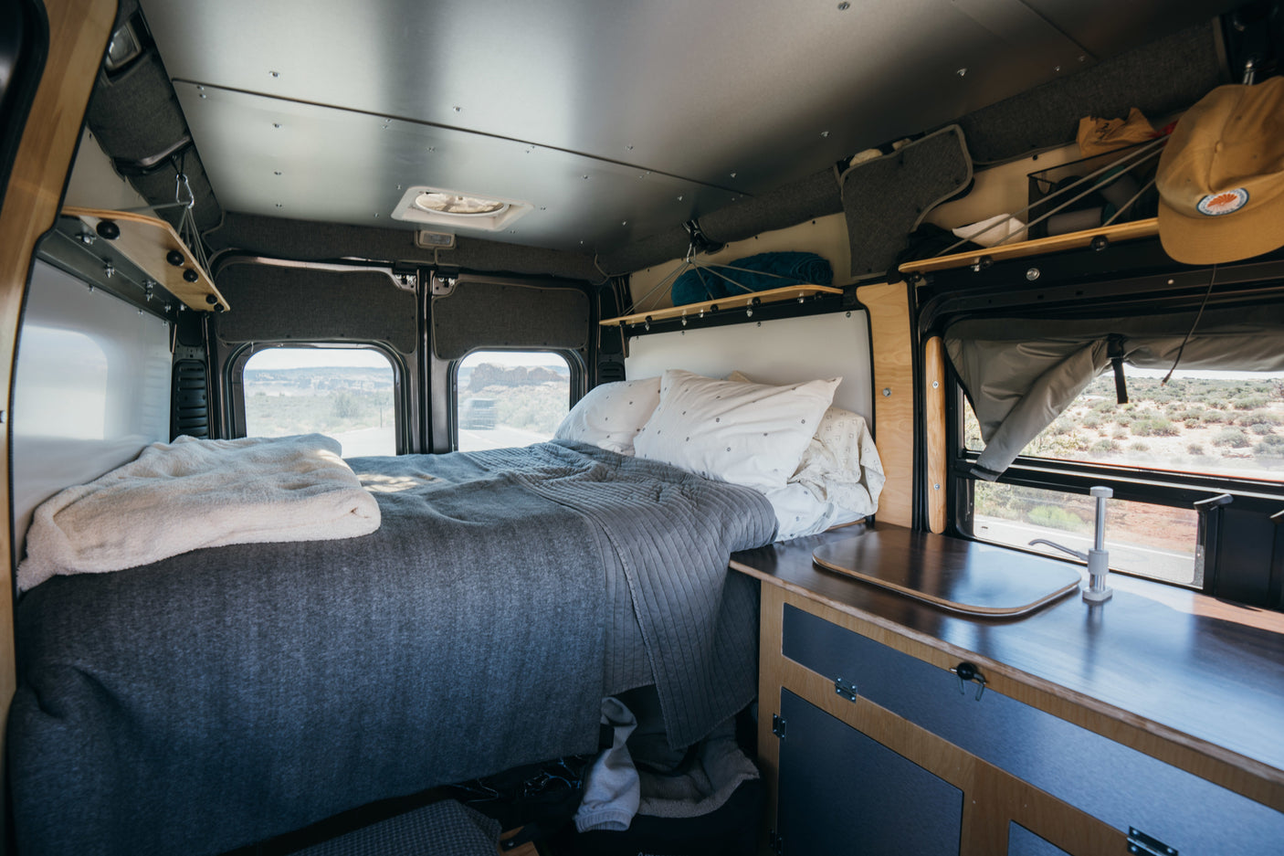 Cozy RV rental interior with bed, kitchenette, and desert views, perfect for a road trip adventure.