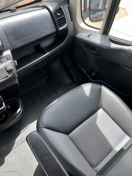 Ram Promaster RV rental interior: passenger dashboard, seat, and patterned rubber floor mat.