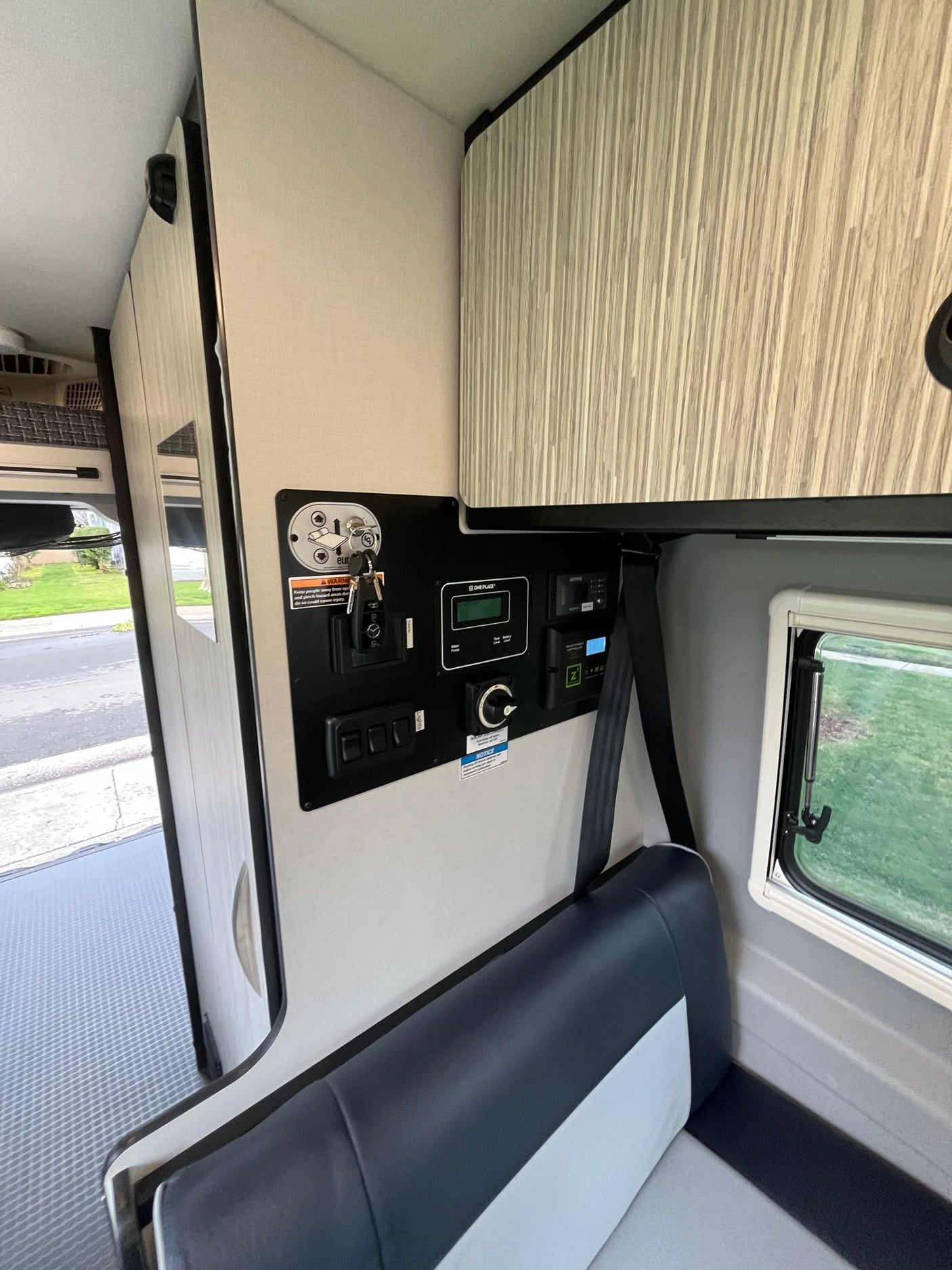 Inside this RV rental, see the main utility control panel, comfortable seating with seatbelt, and overhead storage. Ready for travel.