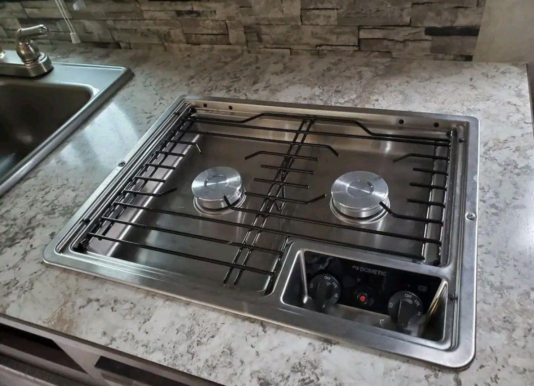 Inside an RV rental: a compact kitchen featuring a stainless steel sink and a Dometic two-burner gas stove for convenient cooking. — photo 8