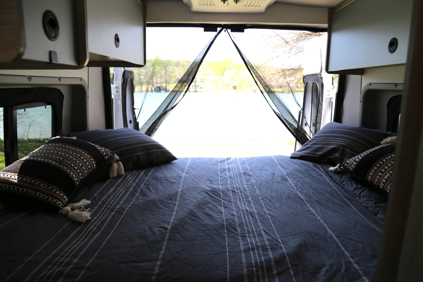  a colorful blanket dries in the sun at a scenic campsite. Water spigot near.|Compact RV rental kitchen with sink — photo 4