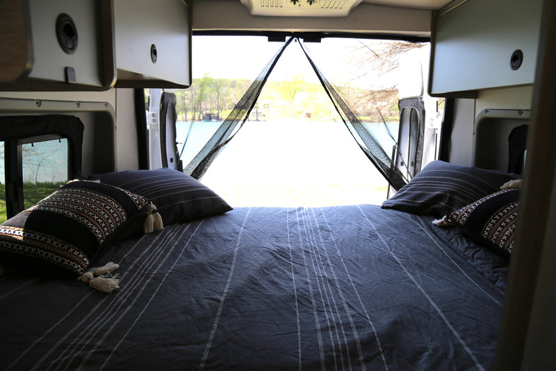  a colorful blanket dries in the sun at a scenic campsite. Water spigot near.|Compact RV rental kitchen with sink — photo 4