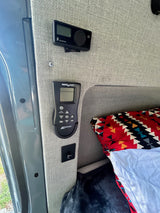 RV rental interior showing Eberspächer heater & MaxxAir fan controls, next to a bed with a colorful pillow.