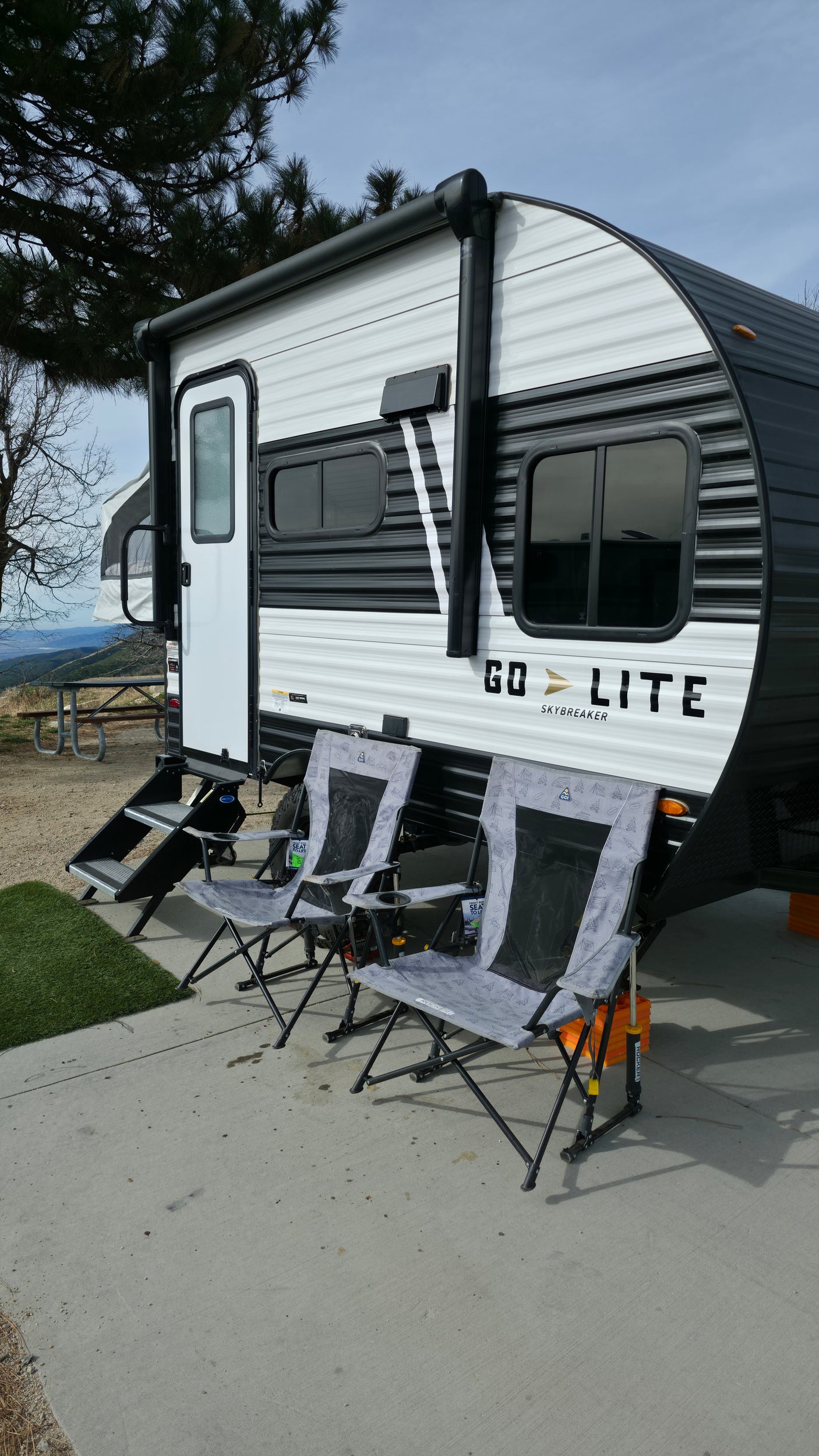 Enjoying an RV rental adventure: a Go Lite travel trailer and cozy camping chairs at a scenic mountain campsite.