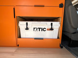 RV rental with bright orange custom cabinetry, including a dedicated pull-out space for a white RTIC cooler.