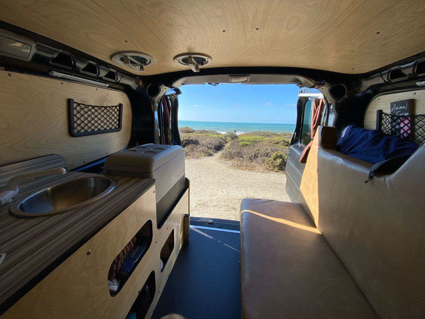  parked in a sun-dappled forest. Ready for your nature escape!|Compact RV rental interior featuring a custom kitchenette with sink — photo 4