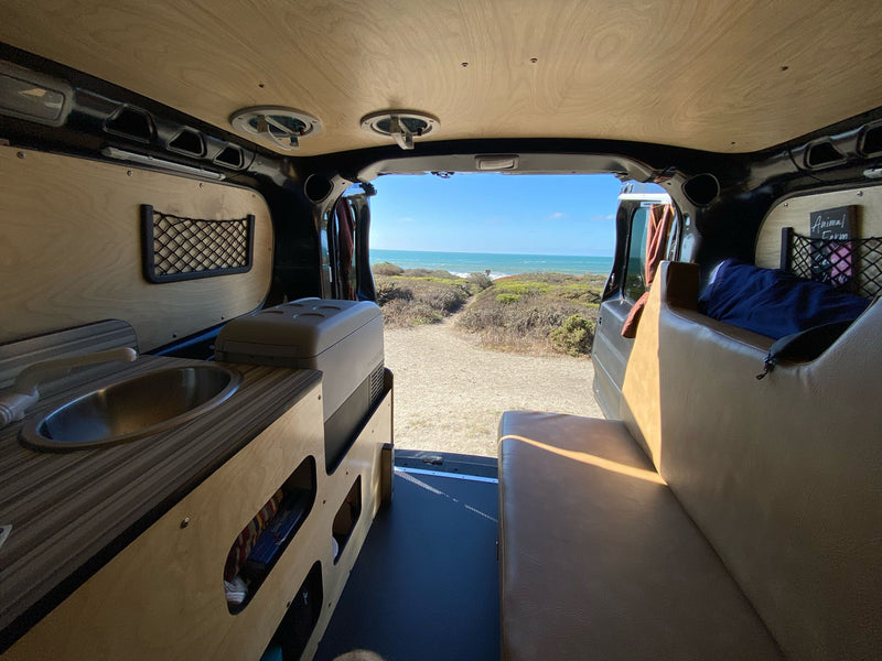  parked in a sun-dappled forest. Ready for your nature escape!|Compact RV rental interior featuring a custom kitchenette with sink — photo 4