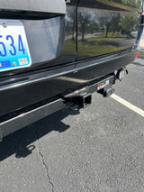 Close-up of an RV rental's rear bumper, highlighting its trailer hitch for towing and electrical connections.