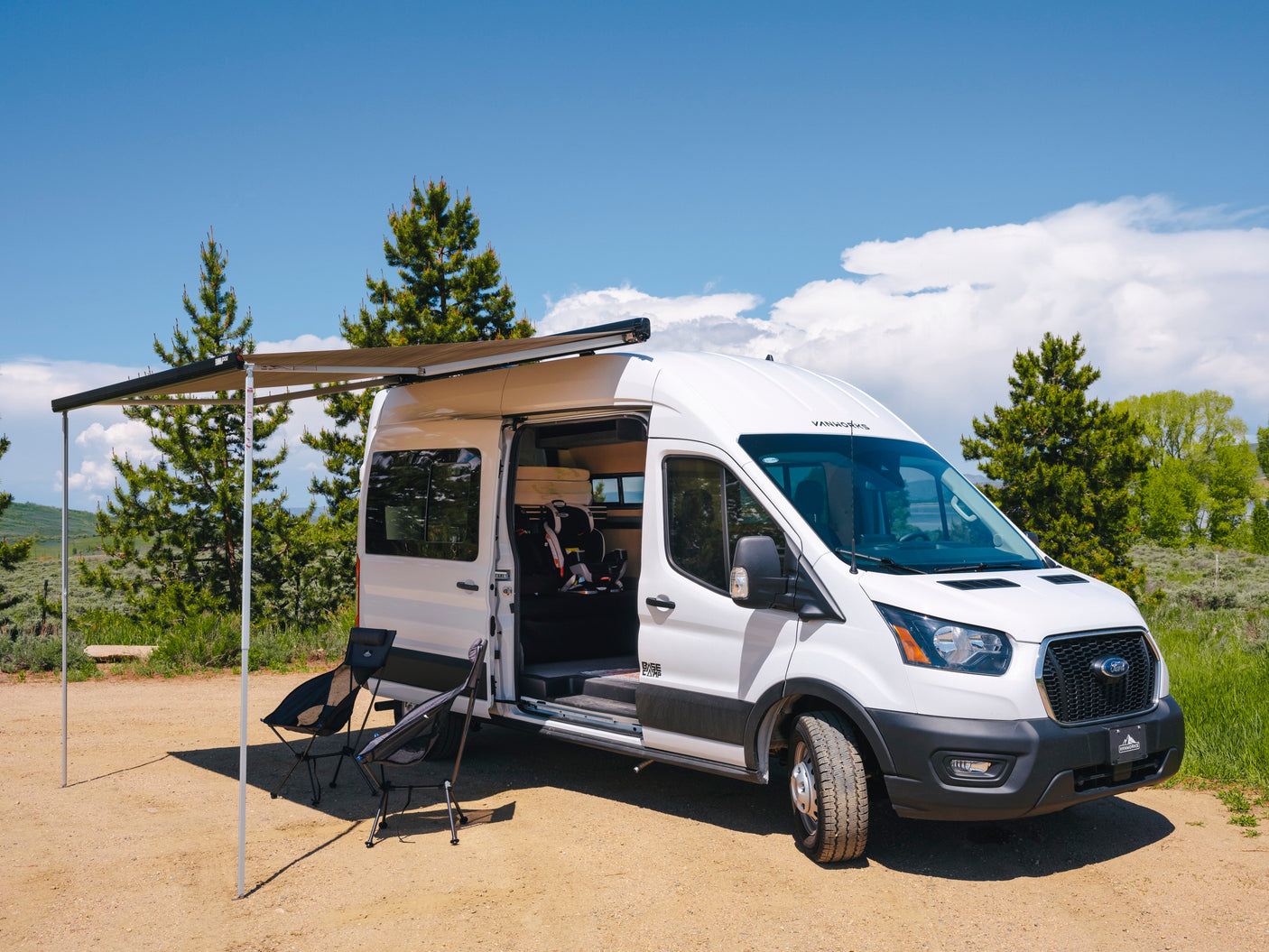 This RV rental camper van, with its extended awning and chairs, is set for a family outdoor adventure.