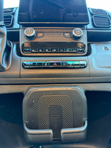 RV rental dash showing a modern infotainment system, climate controls, and a "RAMCHARGER" wireless phone charger.