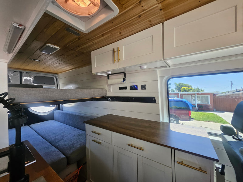 Spacious and modern RV rental interior with a wooden ceiling, white cabinets, and cozy sleeping/seating areas. — photo 4
