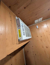 RV rental: Angled view of a wall-mounted AC unit within wood paneling. Includes power & cable outlets, plus a Command hook.