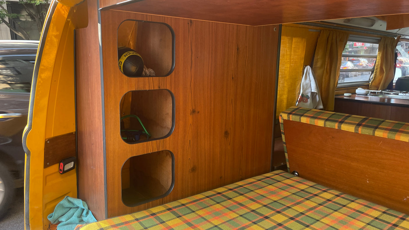 This RV rental offers a retro escape: wood-paneled storage, vibrant plaid upholstery, & a view of city life.