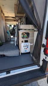 RV rental interior: open rear door reveals a versatile living space with adaptable seating, storage, and utility panel.
