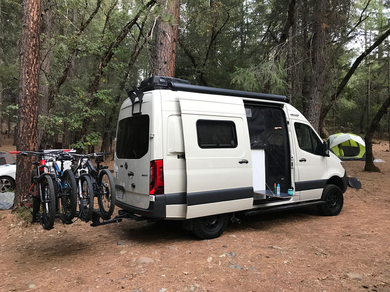  parked at a shaded campground site with an extended awning and picnic table.|This sleek RV rental — photo 12