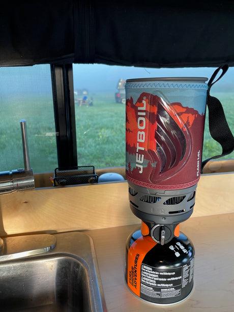 Jetboil camping stove ready for use in an RV rental kitchen on a misty morning, perfect for coffee while traveling.