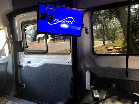 RV rental interior with mounted TV, headphones, and a view of the road, offering entertainment on the go.