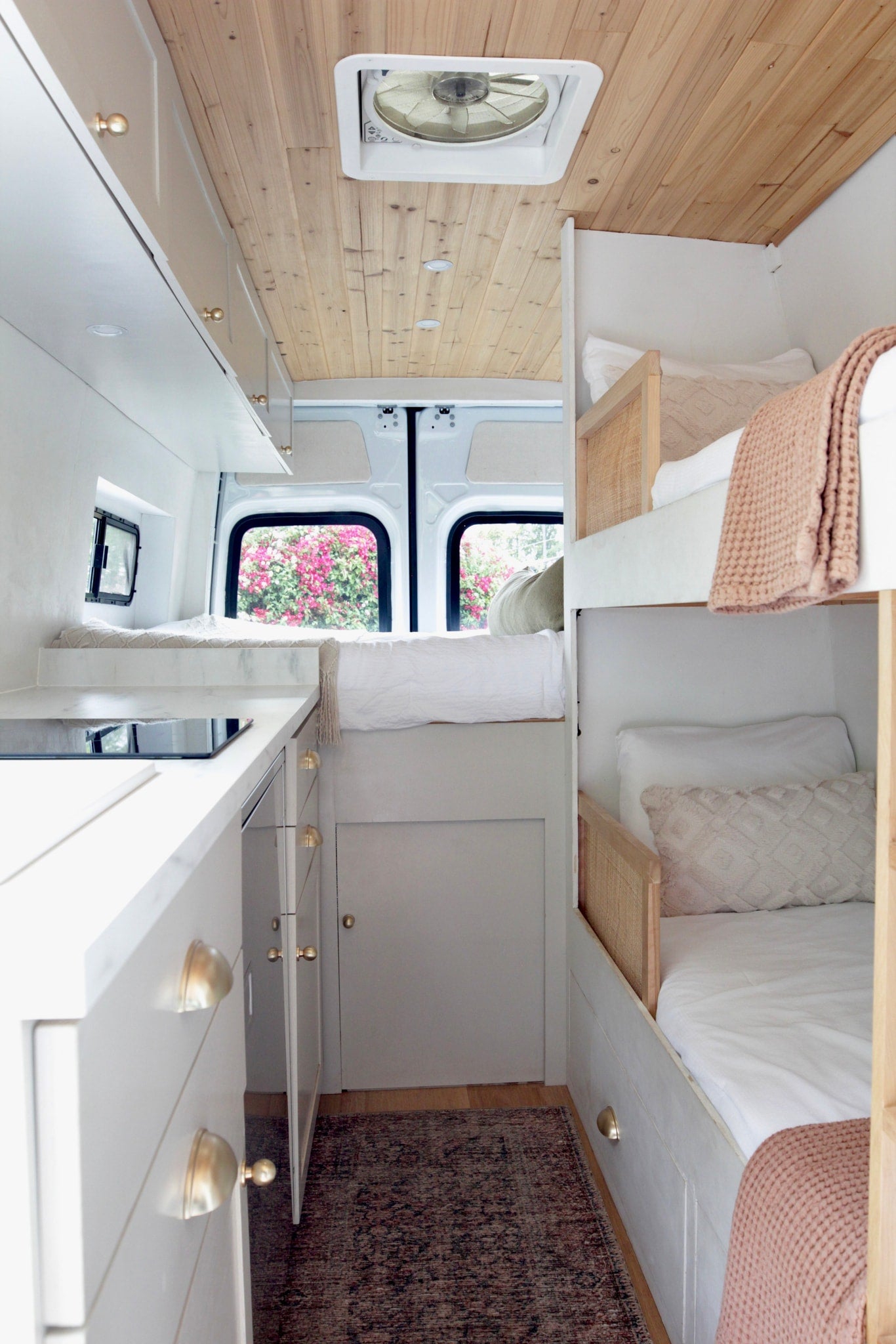 RV rental: Bright, modern camper interior with a cozy bunk bed area, sleek kitchenette, and wood-paneled ceiling. — photo 2
