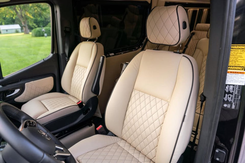  parked on a gravel path with green grass and trees in the background.|Luxury Mercedes-Benz RV rental interior: spacious driver's cabin with plush beige quilted seats — photo 15