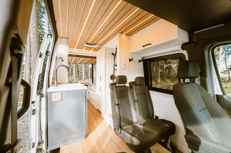 This modern RV rental features a compact kitchen, sleek wood ceiling, rear seating, and a shower, ideal for travel. — photo 1