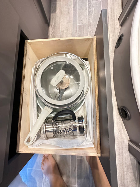 Organized rv rental kitchen drawer: a pot, pan, and French press neatly stored for travel cooking.
