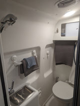 Step inside a clean, compact RV rental bathroom featuring a shower, sink, toilet, and smart storage solutions.