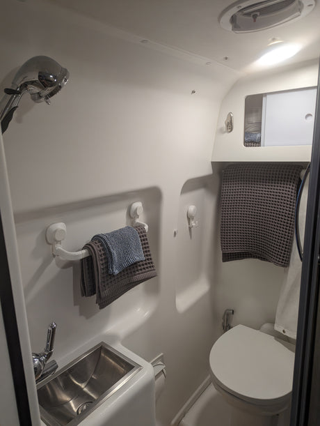 Step inside a clean, compact RV rental bathroom featuring a shower, sink, toilet, and smart storage solutions.
