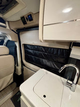 Modern RV rental interior featuring a kitchen sink, overhead cabinets, and climate controls, ideal for comfortable travel.