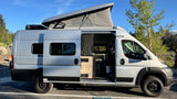 Silver pop-top camper van rv rental parked outdoors, its side door open to reveal a compact interior setup.