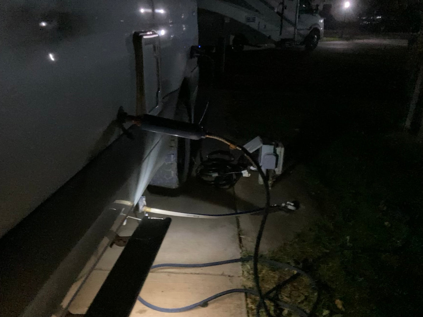 Nighttime RV rental parked with essential power and water hookups at a campground.