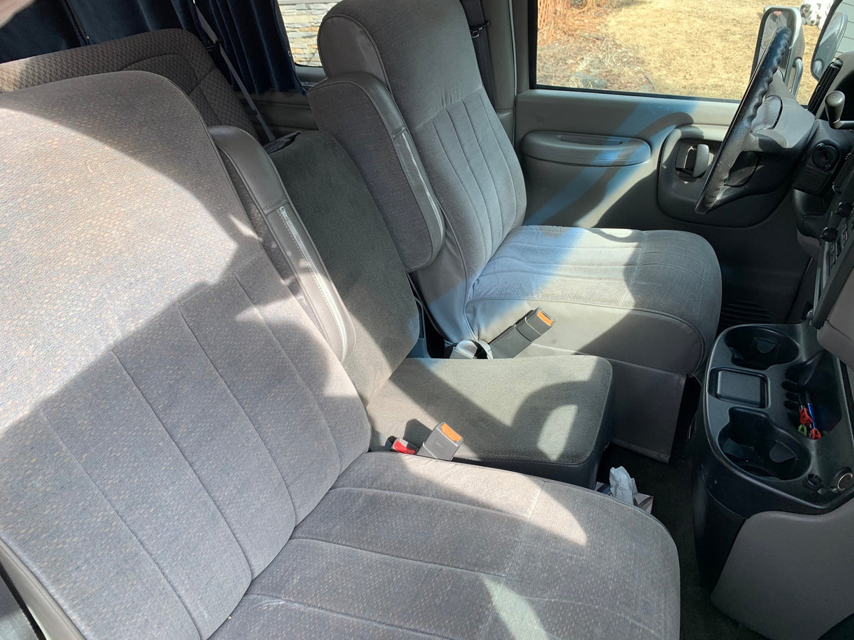 Spacious grey interior of an RV rental, showing comfortable cloth seats with armrests and a front console. — photo 11