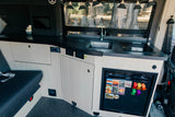 Inside an RV rental: a modern kitchenette with sink, cooktop, fridge, and ample light wood cabinetry for comfortable travels.