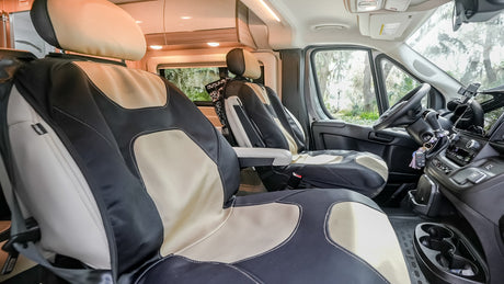 Experience comfort in this RV rental's front cabin. Features two-tone seats, driver controls, and a scenic view outside.